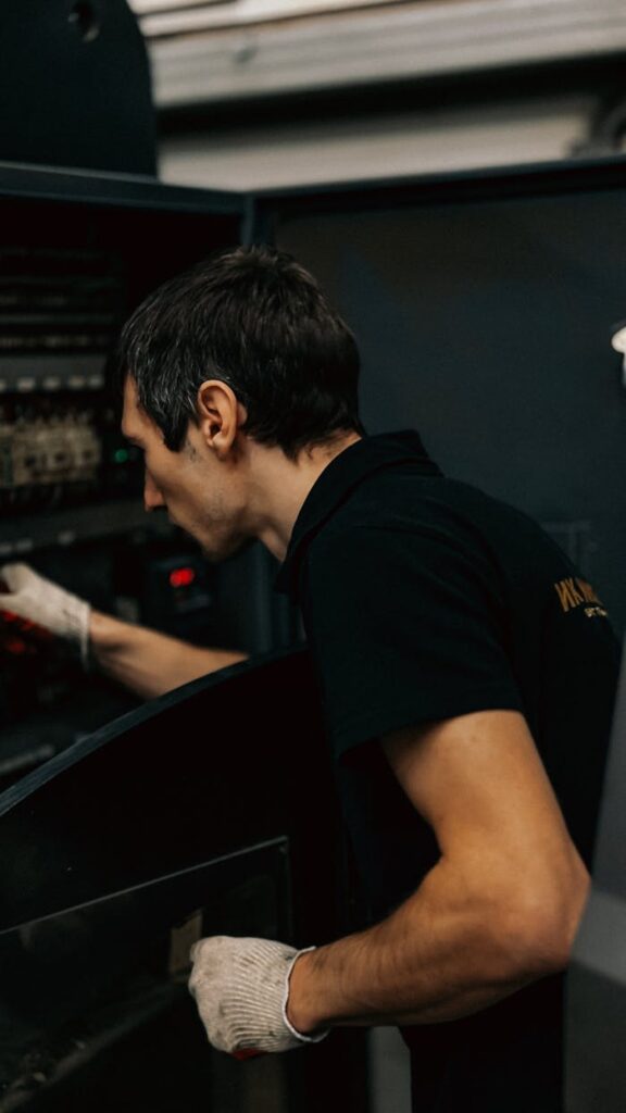 A focused technician examines industrial machinery inside a workshop.
