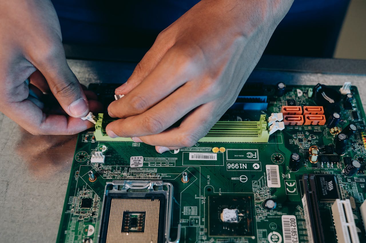 Hands carefully assembling a computer motherboard, showcasing technical craftsmanship in electronics.